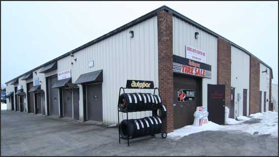 Denis Auto Centre building on Sweetnam Drive, with a row of garage bays and a tire rack at the door